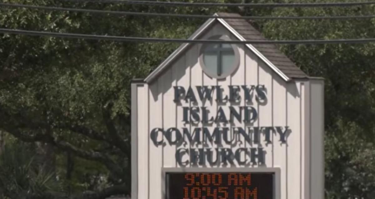 A sign for Pawleys Island Community Church stands in front of green trees.