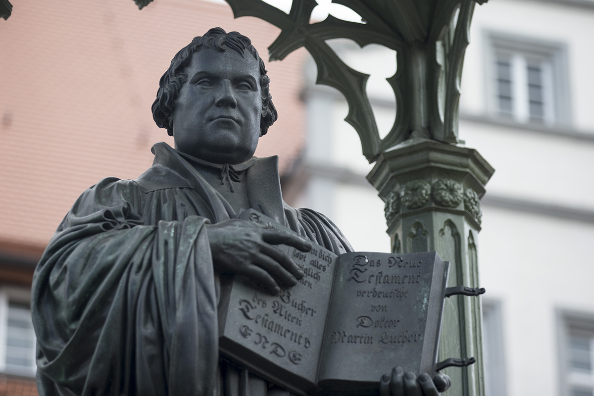 A bronze statue of a man holding an open book.